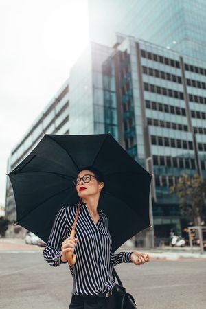 Businesswoman on city street with umbrella