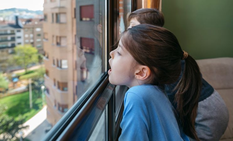 Two children in coronavirus lockdown playing breath on the glass