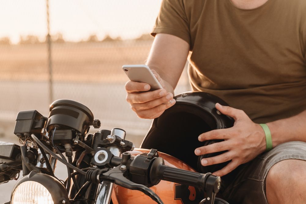 Man sitting on motorcycle and surfing mobile