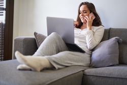 Smiling woman browsing on laptop and sitting on settee