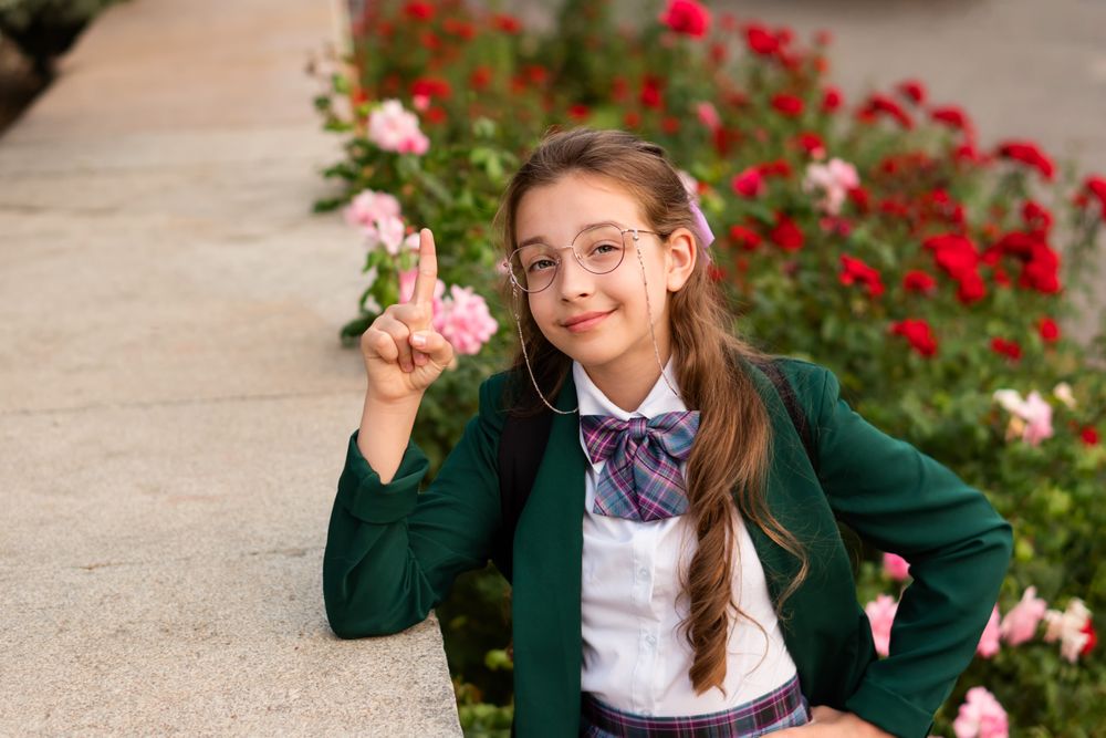 Girl in school uniform smiling and raising finger