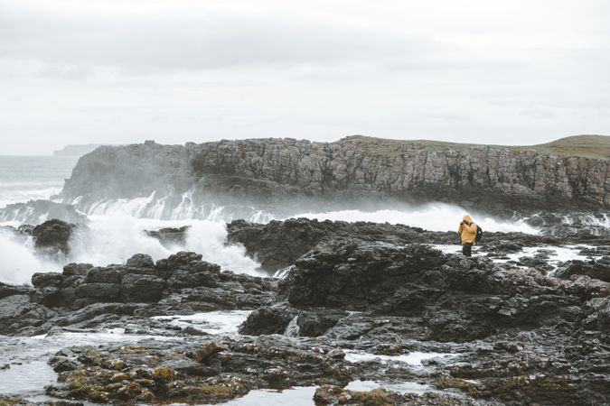 Man standing on rock and taking picture of sea