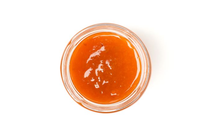 Glass jar with apricot jam isolated on blank background