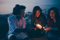 Group of friends light sparklers at dusk