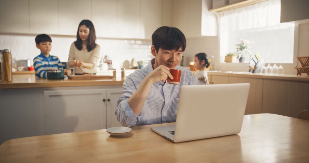 Korean Family at Home: Young Father Using Laptop Computer for Working Remotely While Waiting for Food