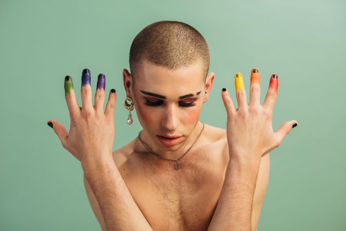 Shirtless man with pride flag colors on his fingers
