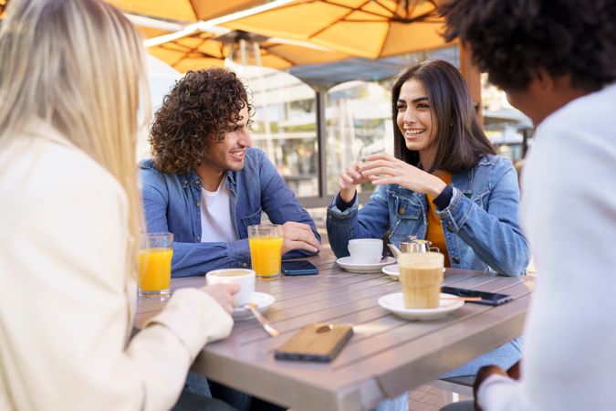 Man and woman laughing with their friends at an outside table