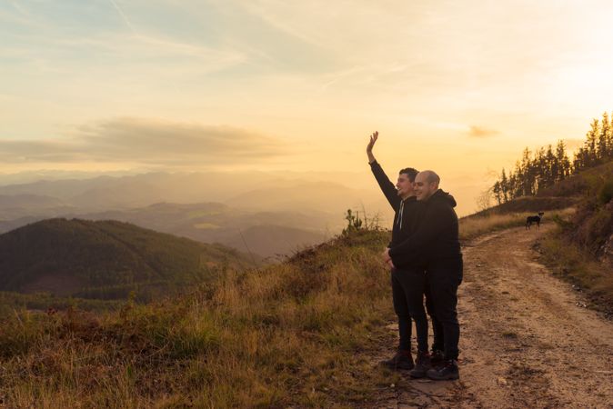 Men hugging on road on hill