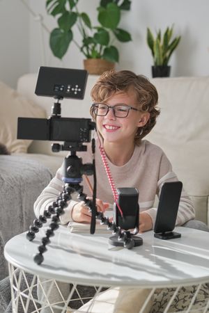 Smiling boy shooting video for blog using professional equipment