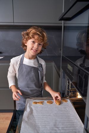 Boy putting cookies into oven
