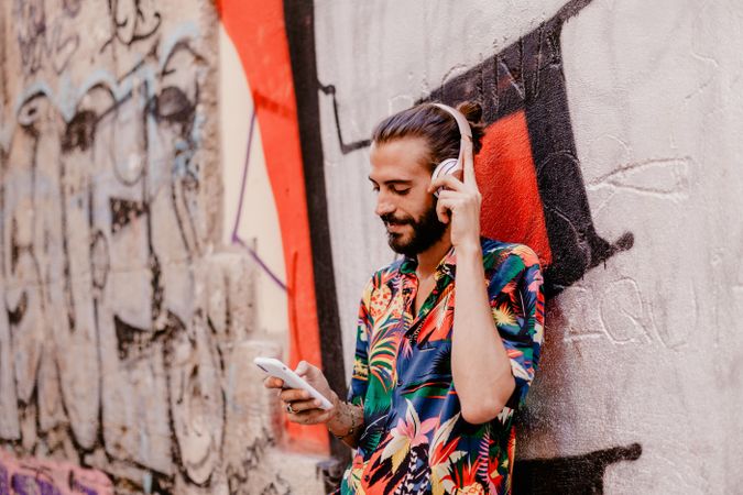 Smiling man listening to music and using smartphone