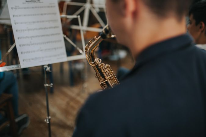 Rear view of young male concentrating on playing saxophone