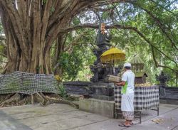 Bali, Indonesia - August, 15 2015: Anonymous man standing near table with religious gifts