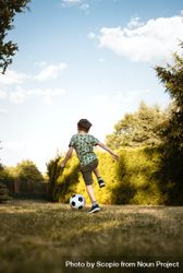 Back view of boy playing soccer in a park 4MwVa0