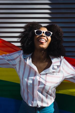 Fun Black woman posing happily with the LGBT flag