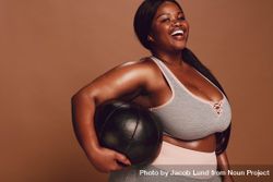 Cheerful plus size Black woman with medicine ball on brown background 5oArzb