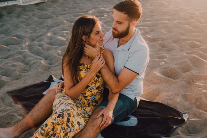 Tender couple embracing and kissing in sunlight on beach