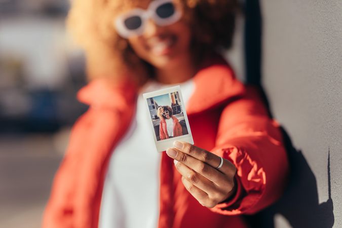 Blur shot of a female traveller on vacation holding a polaroid picture to camera