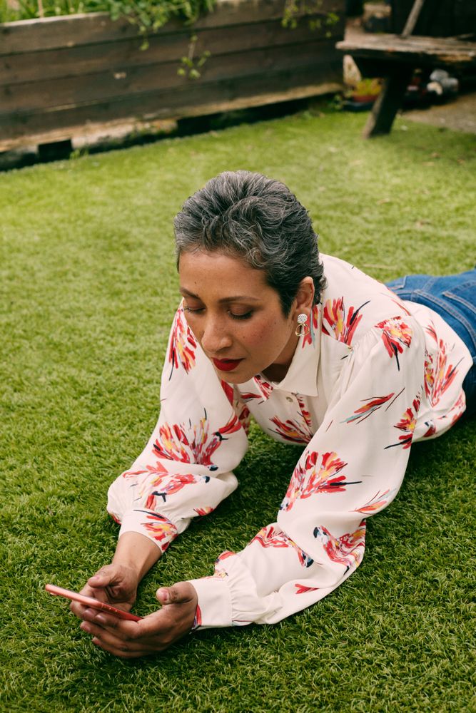 Woman laying on grass looking at mobile phone outside