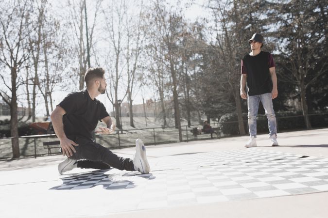Guy looking at man dancing break dance in park