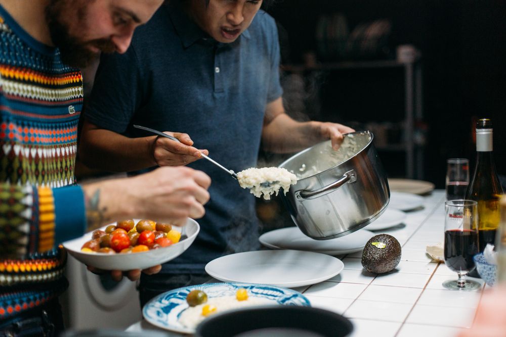 Two friends serving risotto with parmigiano reggiano