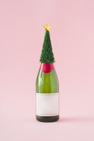 Champagne bottle with Christmas tree against pink background