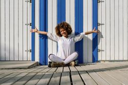 Young Black woman on roller skates sitting in front of a beach hut