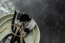 Top view of table setting with dark cutlery & string on concrete background with copy space