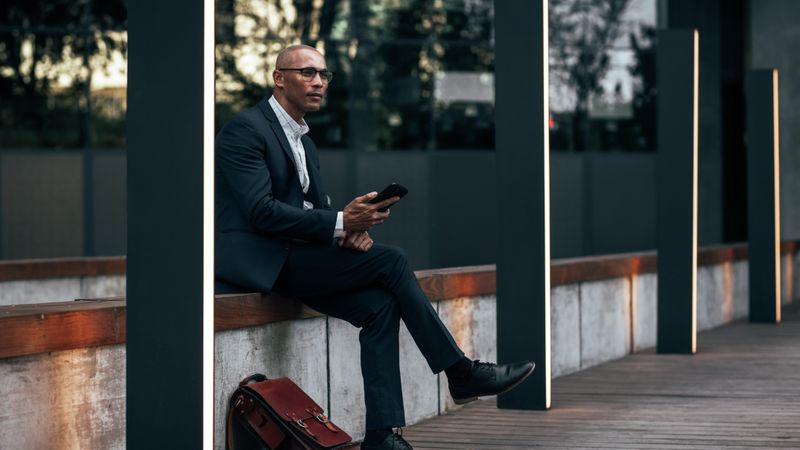 Businessman sitting outdoors with cell phone