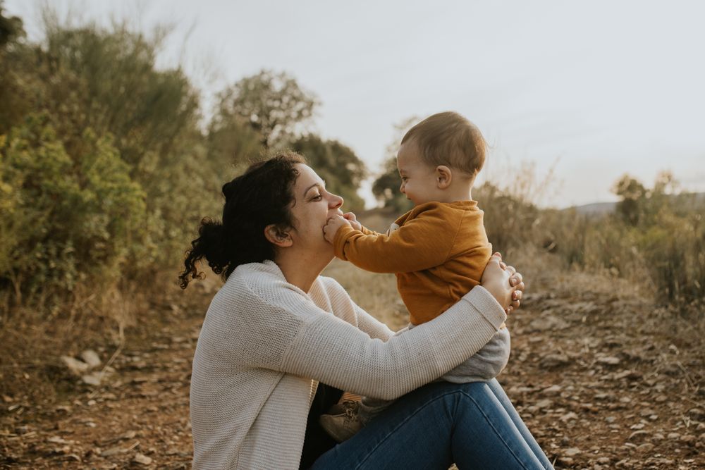 Mother playing with her baby son on a walking path on a fall day