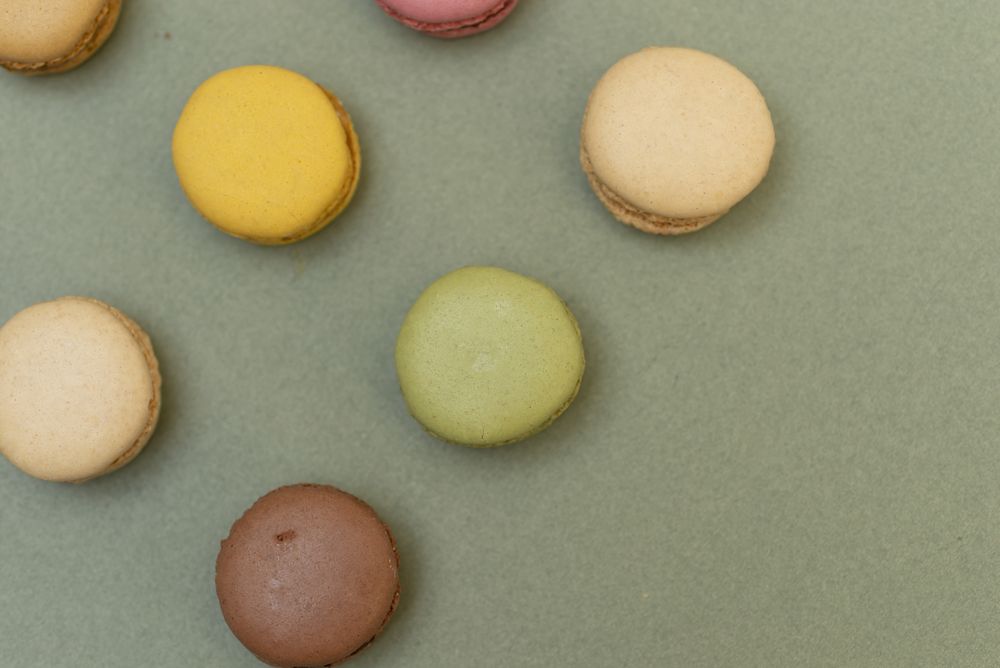 Rows of macaroons on green table from above