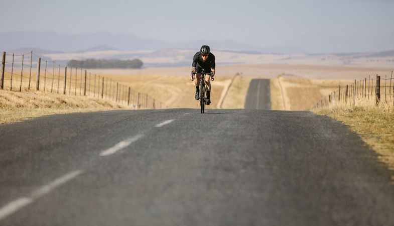 Cyclist riding a bike on countryside landscape road