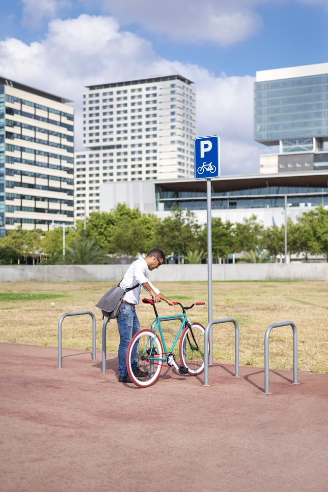 Male with colorful bike using bicycle rack in city