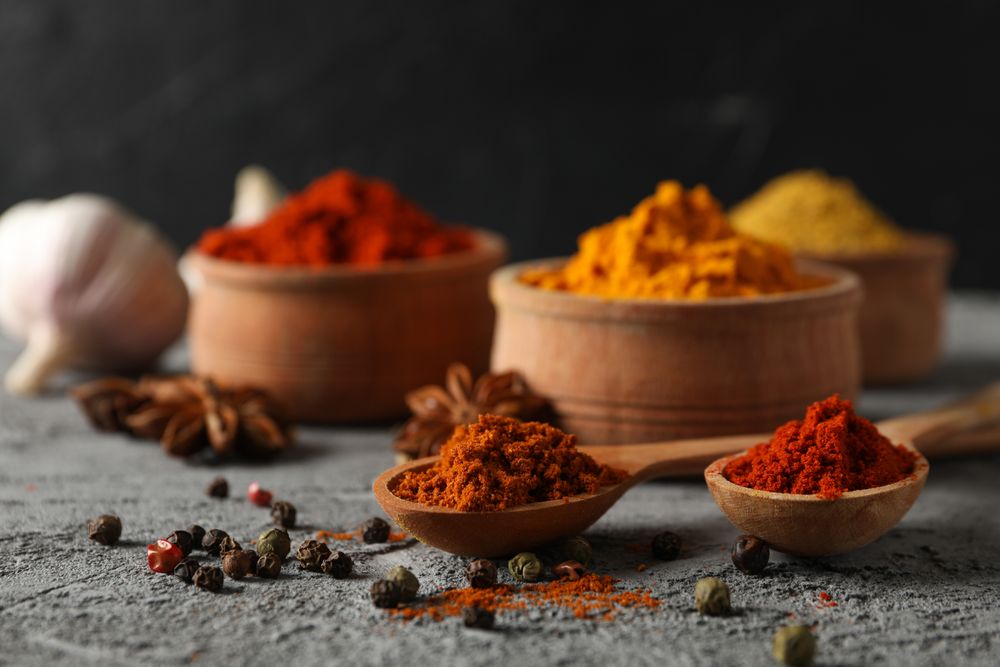 Side view of bowls of spices and garlic bulb