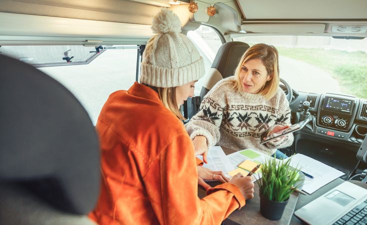 Female friends working remotely in back of van while on a road trip