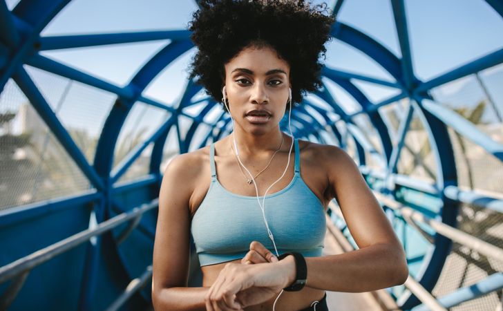 Young fitness woman with smart watch looking at camera