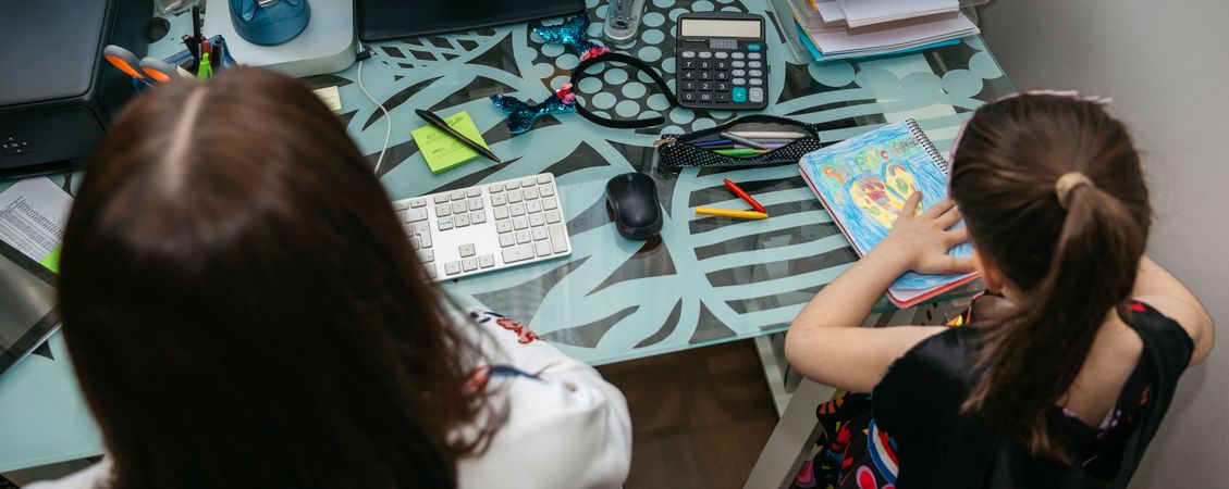 Woman teleworking with her daughter drawing