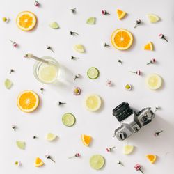 Colorful pattern made of orange, lemon, lime and flowers with lemonade and vintage camera