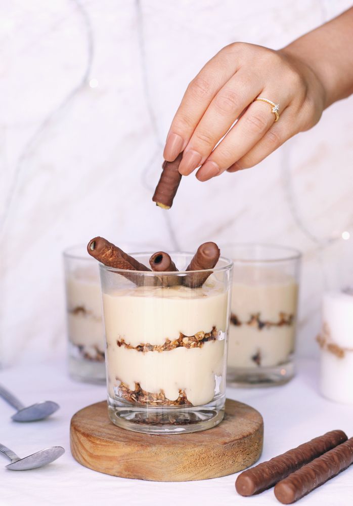 Person putting chocolate-coated stick-o in glass