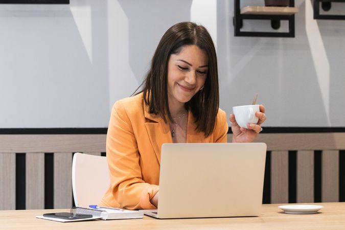 Optimistic woman working on laptop in cafe