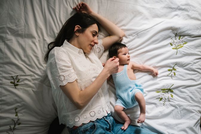 Mother and baby lying on bed