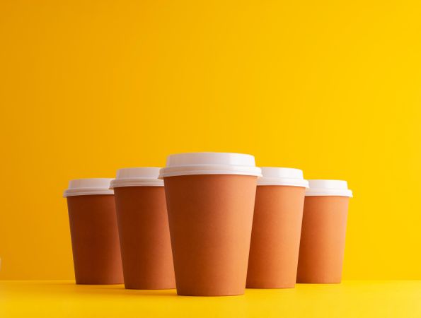Disposable coffee cups on yellow background