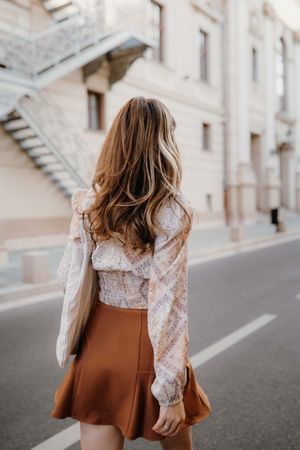 Back view of woman in brown skirt walking on street