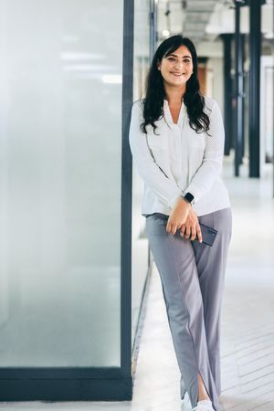 Businesswoman standing and smiling at the camera holding a phone