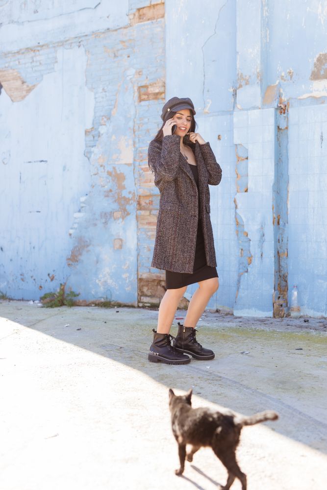 Hispanic woman talking on smartphone and going near wall and cat