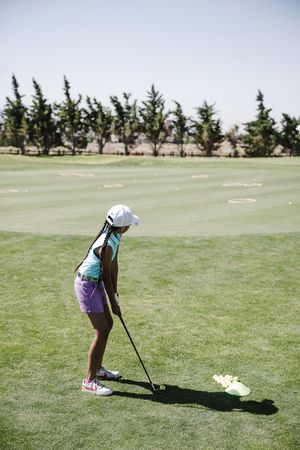 Back view of young girl playing golf