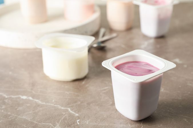 Composition with plastic cups with yogurt on grey table, space for text