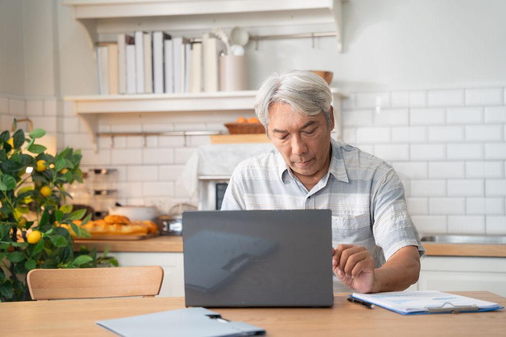 Asian older man learning or working with laptop in the morning at home