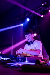 Happy Young DJ mixing in a disco with neon lights