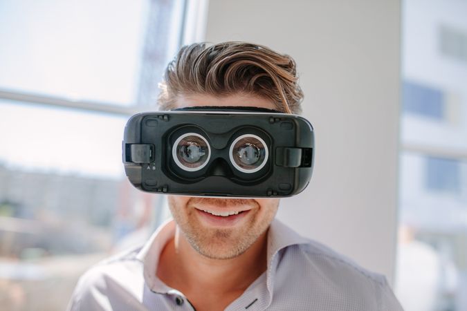 Close up of happy young man wearing virtual reality goggles